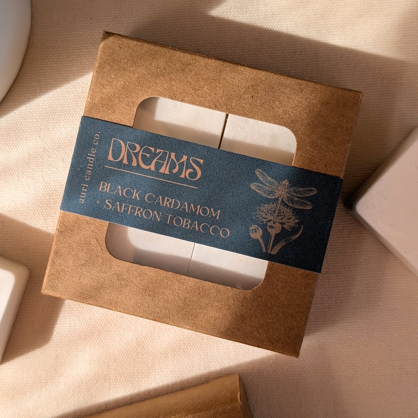 A package of Dreams wax tarts in Black Cardamom + Saffron Tobacco scent, with eco-friendly kraft packaging and a label featuring the product name and an insect illustration.