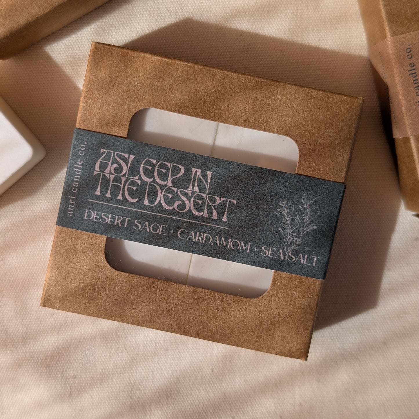 Candle packaging with a label on a beige fabric background