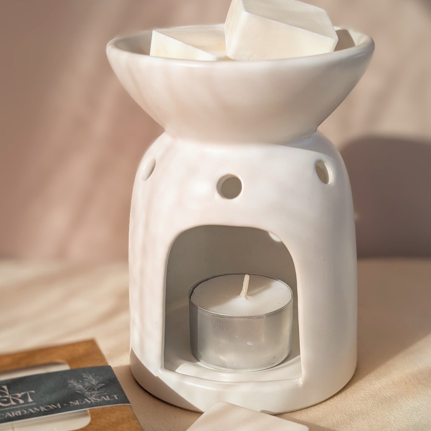 White ceramic oil burner with candles on a soft background